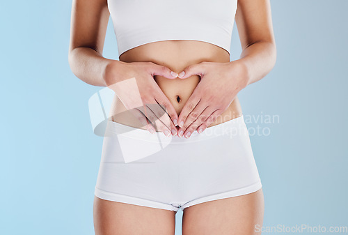 Image of Healthy stomach, heart and woman hands, wellness and gut health, body contouring and diet on studio blue background. Fitness model belly love, digestion and skincare, laser liposuction and abdomen