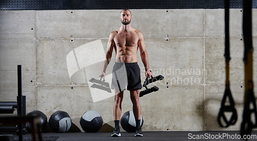 Image of A muscular man performs shoulder exercises in a modern gym, showcasing his strength and dedication to fitness.