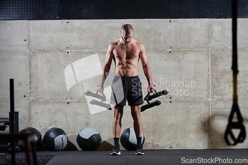 Image of A muscular man performs shoulder exercises in a modern gym, showcasing his strength and dedication to fitness.