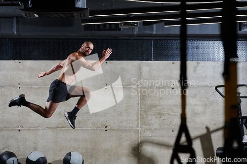 Image of A muscular man captured in air as he jumps in a modern gym, showcasing his athleticism, power, and determination through a highintensity fitness routine