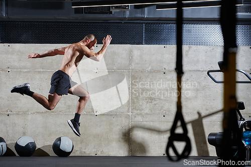 Image of A muscular man captured in air as he jumps in a modern gym, showcasing his athleticism, power, and determination through a highintensity fitness routine