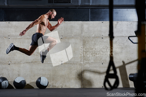 Image of A muscular man captured in air as he jumps in a modern gym, showcasing his athleticism, power, and determination through a highintensity fitness routine