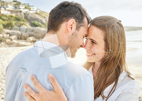 Image of Couple, love and hug on a beach together for an engagement honeymoon or anniversary by the sea. Young man and woman smile feeling happy and romantic by the ocean water and sand with happiness