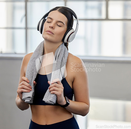 Image of Towel, tired or fitness woman with music headphones in gym workout, health training or wellness exercise for heart cardio. Sweating, exhausted or fatigue sports person listening to motivation radio