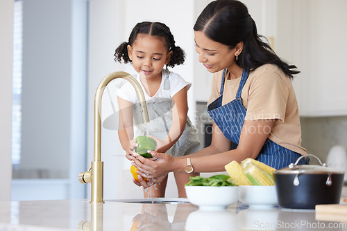 Image of Kitchen, mother and child washing vegetable to cook dinner, lunch or breakfast together at house. Happiness, bonding and mom cleaning a green pepper before cooking food with girl kid in family home.