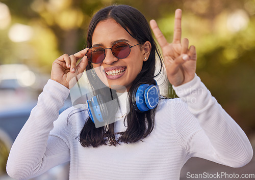 Image of Music, headphones and peace hand sign of a woman from mexico in nature on a walk. Portrait of a person with a happy smile, sunglasses and gesture streaming audio outdoor feeling free in a nature park