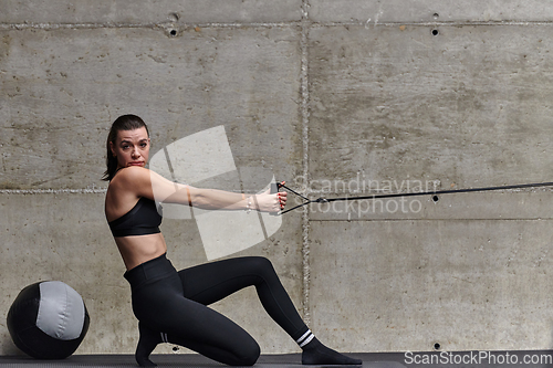 Image of A fit woman in a modern gym performs arm exercises with determination, showcasing her strength and sculpted muscles as she works towards her fitness goals.