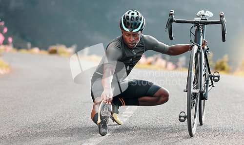 Image of Outdoor, cycling and cyclist doing stretching exercise by his bicycle on road in mountain. Sports, training for fitness and man athlete doing warm up before cardio cycle workout with bike in nature.