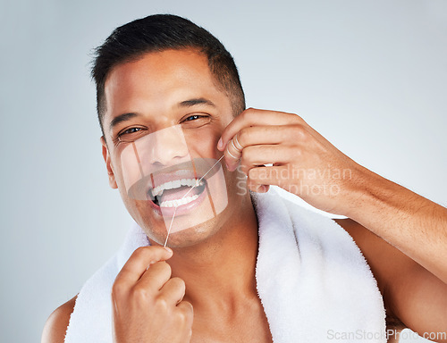 Image of Man, dental flossing and teeth with smile for clean hygiene and health against a grey studio background. Portrait of happy toothy male smiling in fresh grooming and floss for mouth, oral and gum care