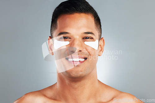 Image of Happy, beauty and eye patches on a grey studio background. Skincare, health and man model with face and facial cosmetics strip or collagen pads for skin wellness, hydration or facial anti aging