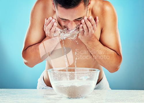 Image of Skincare, cleaning and man with water on face satisfied with hydration, grooming and hygiene. Wellness, cleansing and healthy routine of model for hydrated skin on blue studio background