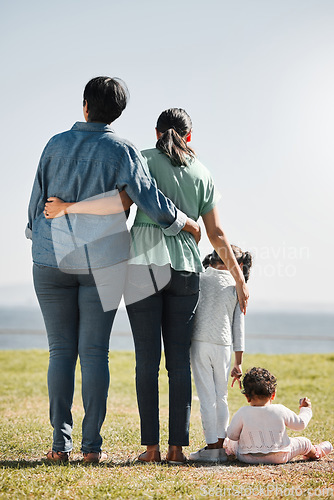 Image of Park, nature and back view of family on grass outdoors with relatives spending quality time together. Love, support and caring grandma, mom and girl with baby bonding together with scenic ocean view.