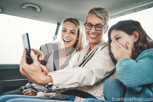 Image of Family, phone and women taking a selfie in the car on road trip adventure. Grandmother, mom and girl smile for picture on smartphone in backseat for memories of holiday, journey and vacation weekend