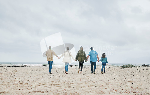 Image of Big family, beach holiday and summer travel with child, parents and grandparents on sand and cloudy sky for love, care and support. Men, women and girl kid walking together holding hands on vacation