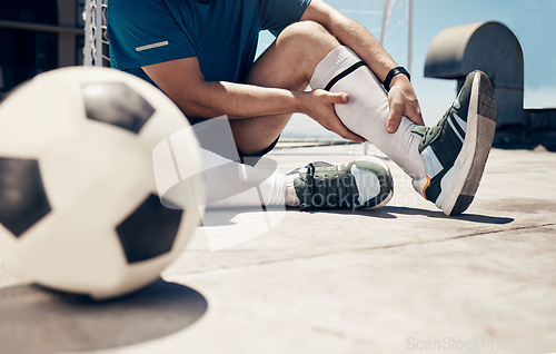 Image of Football, fitness or man with leg injury while training, exercise or soccer workout on roof of building outdoor. Wellness, health or soccer player with muscle pain, bone emergency or sports accident