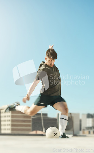 Image of Man, soccer ball and kick in city for goal, shooting or workout on rooftop of building, urban or metro. Soccer player, football and striker at training, exercise and fitness in sports in summer sun