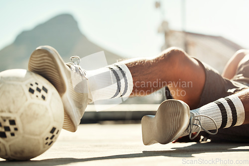 Image of Soccer, ball and man with slide challenge during match, practice or training on concrete court in the city. Football, fitness and exercise in sports game with athlete legs, shoes and tackle outdoor