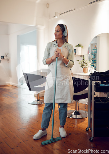 Image of Salon, headphones and woman cleaner sweeping her workplace while listening to music, radio or podcast. Broom, cleaning and girl maid doing domestic work in a beauty parlor while streaming audio.