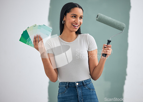 Image of Interior design, green paint and woman doing home renovation with paintbrush roller and color cards in hand. Decoration, home improvement and creative black woman excited for painting wall and diy