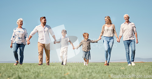 Image of Family, love and walking with smile, together and happy on a field in nature with a blue sky background. Big family with kids, parents and grandparents enjoy weekend, holiday and summer in Germany