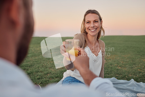 Image of Toast, juice and couple on a date in a park for love in marriage together during summer. Happy, smile and young woman cheers with a drink and a man on a picnic in nature for happiness and peace