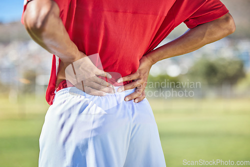 Image of Field, soccer and man with back injury in game tournament with pain, inflammation and backache. Football, athlete and accident in match with player holding body muscle for pressure relief.