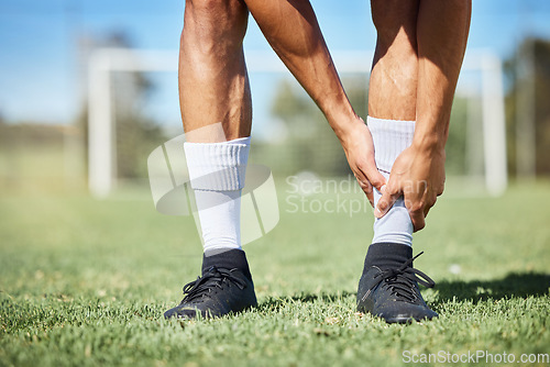 Image of Sports, soccer and ankle injury on grass with self assessment of physical pain at athlete game. Hurt, injured and joint discomfort of football man on field checking painful leg at competition.