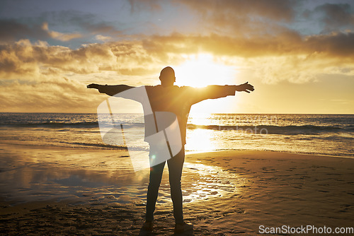 Image of Worship, sunrise and silhouette of man at the beach standing with arms raised. Faith, religious and spiritual person looking at sun, ocean and sky in morning feeling calm, peace and hope in nature