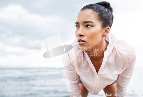 Image of Fitness, break and running with a sports woman tired outdoor by the ocean after a workout. Training, exhausted and exercise with a young female athlete exercising alone on the beach by the ocean