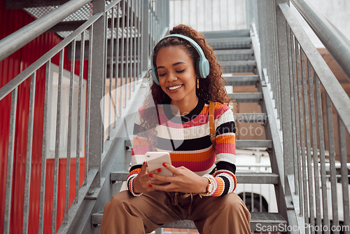 Image of Phone, headphones and black woman on stairs in city streaming music, audio or radio. Gen z, earphones and Brazilian student on 5g mobile, texting or internet surfing, social media or web browsing.