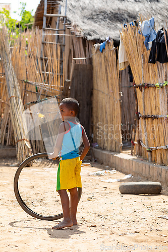 Image of Young boy standing on a dirt road holding a tire Miandrivazo, Madagascar