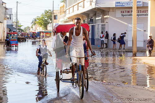 Image of Traditional rickshaw bicycle with Malagasy people on the street of Toliara, one of the ways to earn money. Everyday life on the street of Madagascar.