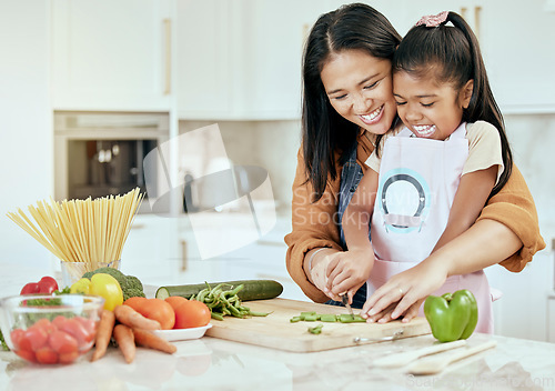 Image of Happy, mother and child learning to cook with smile for help, guidance and support in the kitchen. Mama helping her little girl cut vegetables, food or meal for healthy diet and fun bonding at home