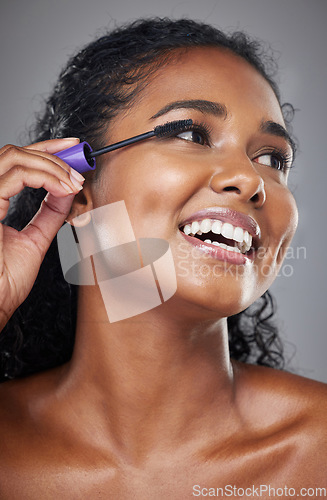 Image of Beauty, makeup and black woman in studio with mascara cosmetics, product and grooming against grey background. Face, eyes and eyelashes by happy, relax and smiling model happy with skincare treatment