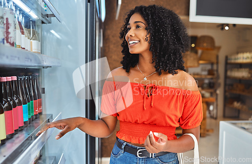 Image of Happy, grocery shopping and woman in a supermarket with drinks at a retail store in Sao Paulo. Happiness, smile and girl from Brazil buying a beverage on a shelf in a food shop while on vacation.