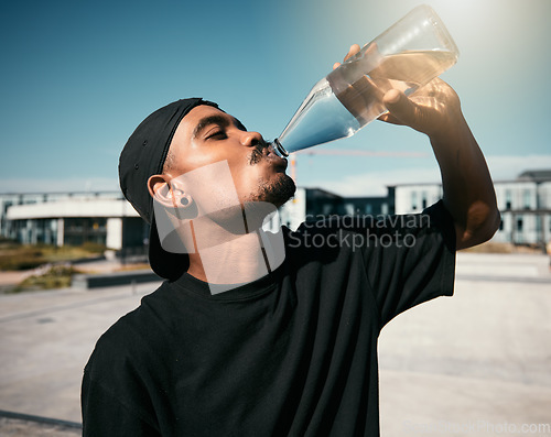 Image of City heat, summer and black man drinking water on concrete road, thirsty gen z outdoor activity. Sun, fun and urban young man with healthy street culture lifestyle and clean water in bottle to drink.