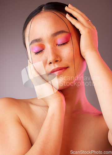 Image of Eyeshadow, asian and beauty woman with hands on face pose with pink and orange cosmetics. Funky, trendy and colorful fashion makeup model for Gen Z cosmetic style on grey studio background.