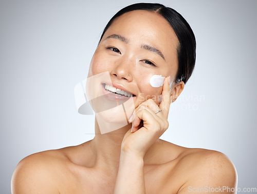 Image of Face, skincare and beauty with a model asian woman applying lotion or moisturizer to her skin in studio. Cosmetics, antiaging and wellness with a young female inside to promote a skin product