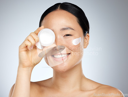 Image of Cream, eye skincare and woman with natural wellness product against grey mockup studio background. Portrait of happy asian beauty model smile with pot of facial lotion with mock up space