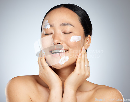 Image of Beauty, skincare and facial product with woman and cream on face for wellness, spa and clean. Sunscreen, cosmetics and health with asian girl for luxury, salon and model lifestyle in gray background