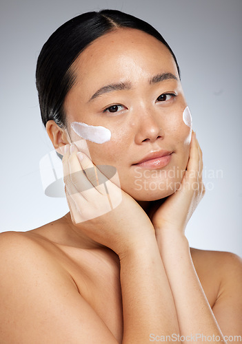 Image of Beauty, asian skincare and woman using face cream or dermatology product for healthy and clean skin. Studio portrait of happy girl model feeling luxury facial or daily cosmetics routine results