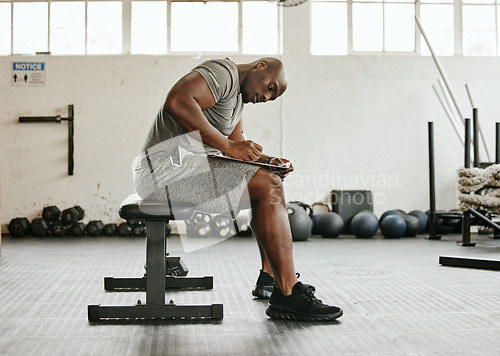 Image of Gym membership, personal trainer and black man writing on clipboard for exercise, training or workout schedule and program. Male sports coach working on health, wellness and fitness plan or goals