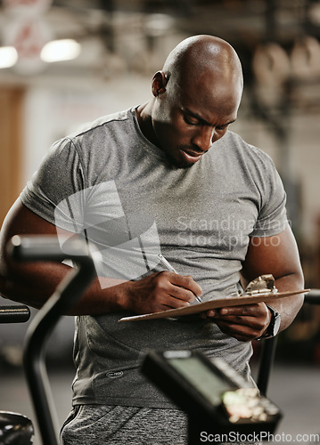 Image of Fitness, clipboard and exercise with a personal trainer in the gym, writing on documents while tracking progress. Training, workout and health with a coach in a performance center for motivation