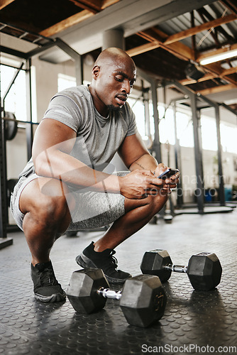 Image of Fitness, phone and online personal trainer at the gym typing or searching on social media in Nigeria. Strong black man, bodybuilder and healthy sportsman networking or texting a digital message