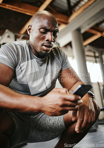 Image of Phone, fitness and sweat with a black man athlete checking his social media after a workout or exercise at the gym. Training, mobile and health with a male tracking his progress on an internet app