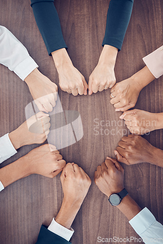 Image of Top view, business people and fist in support circle, team building or collaboration motivation for success goals or target mission. Men, women or worker hands in huddle on table for diversity growth