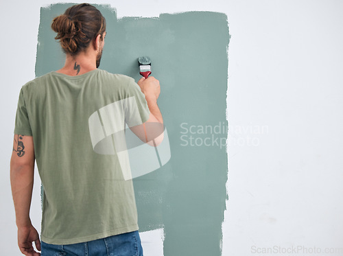 Image of Painting, brush and renovation with a man doing interior DIY in a room for improvement and remodel of home. Young man, decoration and work with green paint on a wall to maintenance in domestic house