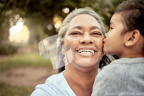 Image of Happy, child and grandmother with smile and kiss for family quality bonding time together in outdoors nature park. Love, senior woman and kid on carefree summer vacation in a forest with happiness