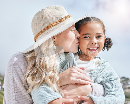 Image of Mother kiss, girl and happy face of a mama and child adoption happiness outdoor for mothers day. Portrait of a hug and love smile of a kid in the summer sun embracing the sunshine in nature