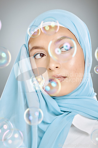 Image of Skincare, bubbles and Muslim model with beauty, idea and thinking against a grey studio background. Young, Islamic and cosmetic woman with a hijab, makeup and vision for dermatology with bubble